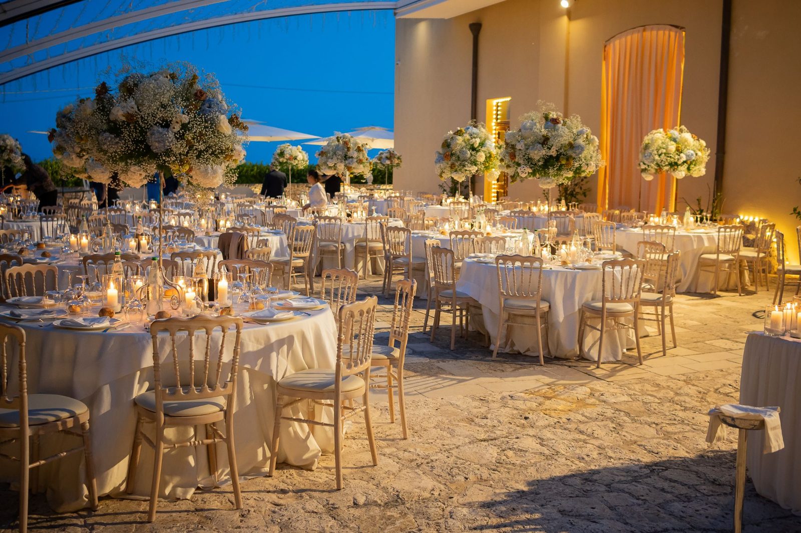 Cena di gala serale sulla terrazza di Cala dei Balcani con candele e alte composizioni di ortensie bianche — Santa Cesarea Terme, Salento