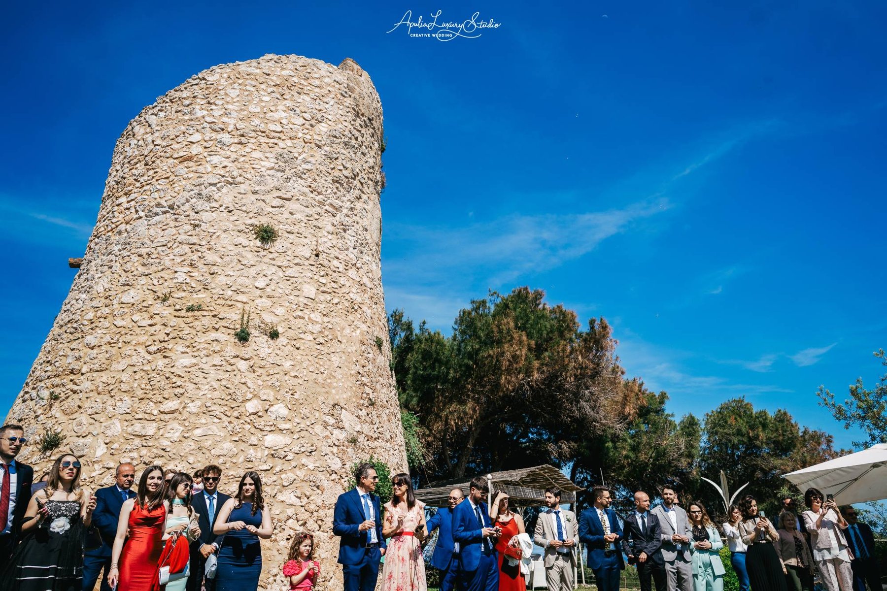 Le mura in pietra della Torre Saracena e gli ospiti di un matrimonio riuniti ai suoi piedi — Cala dei Balcani, Santa Cesarea Terme, Salento
