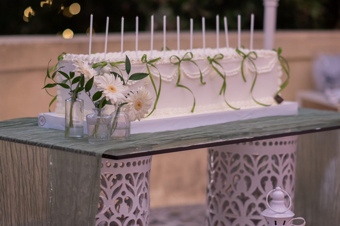 Gâteau de mariage blanc aux rubans verts, gerberas et bougies pour la découpe lors d&rsquo;une réception intime &mdash; Cala dei Balcani, Salento